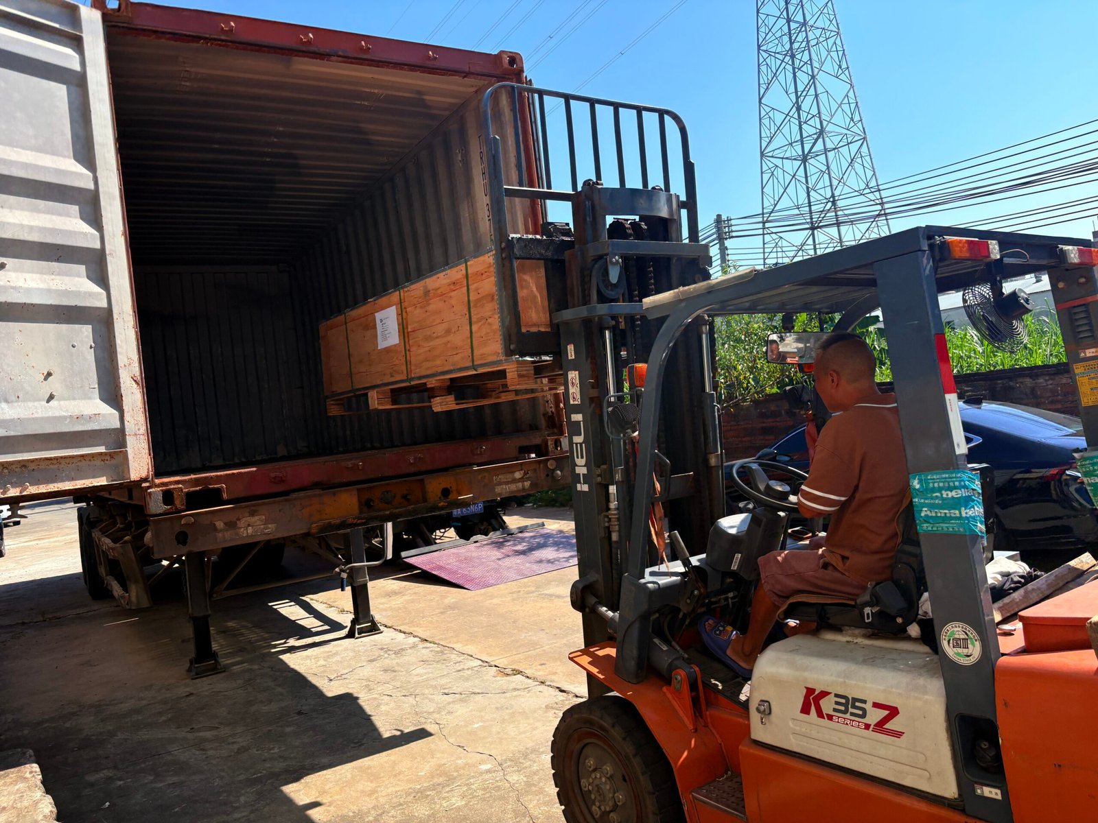 Forklift moving packed office furniture into a shipping container